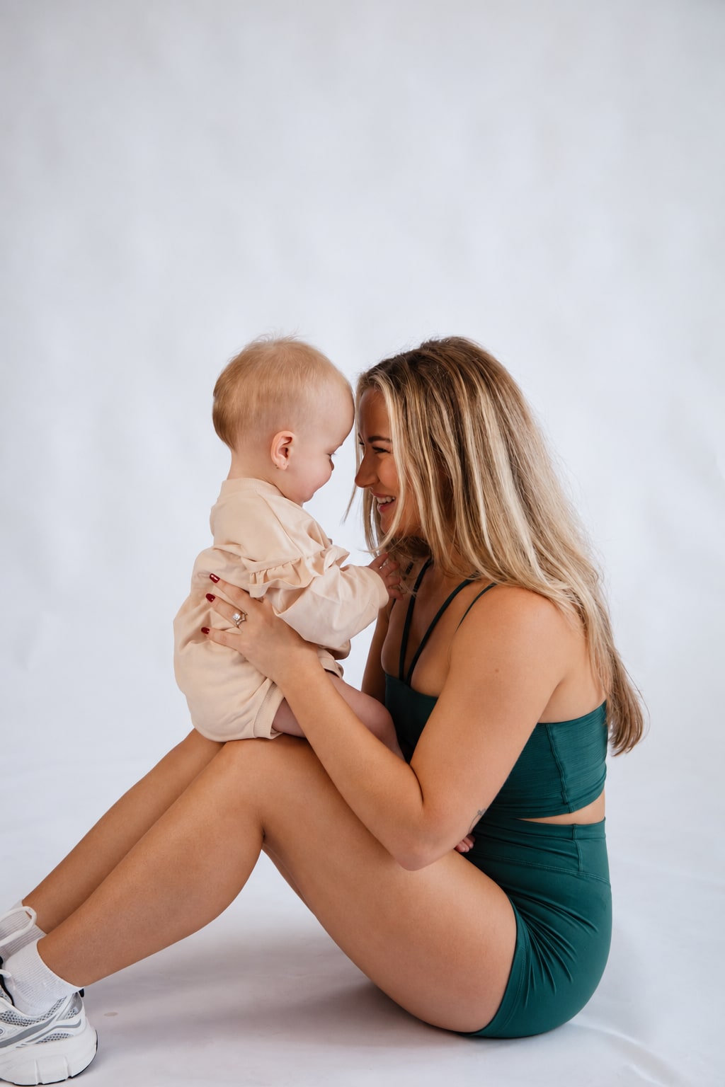 Madison sitting on the floor with her baby daughter on her lap, foreheads touching.