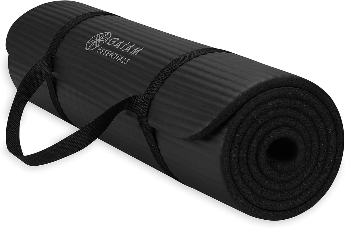A thick black exercise mat, half rolled, with a carrying strap.